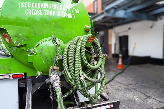 a grease trap being pumped by a sanitation technician in Lake Clear